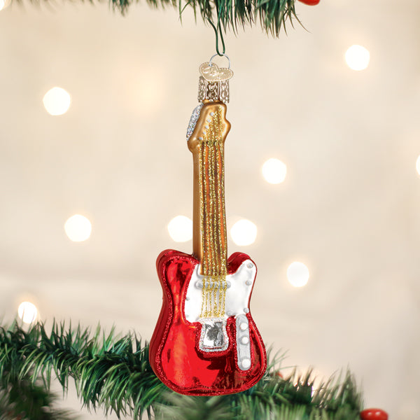 Red guitar-shaped Christmas ornament hanging on a tree with lights in the background