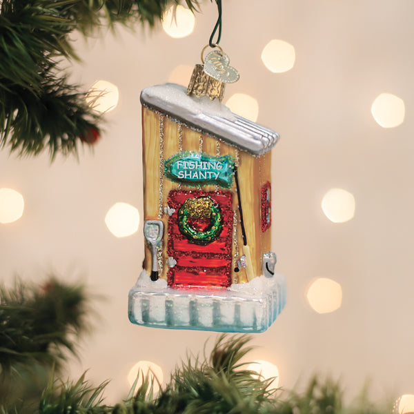 Christmas ornament of a fishing shack with a wreath on a decorated tree.