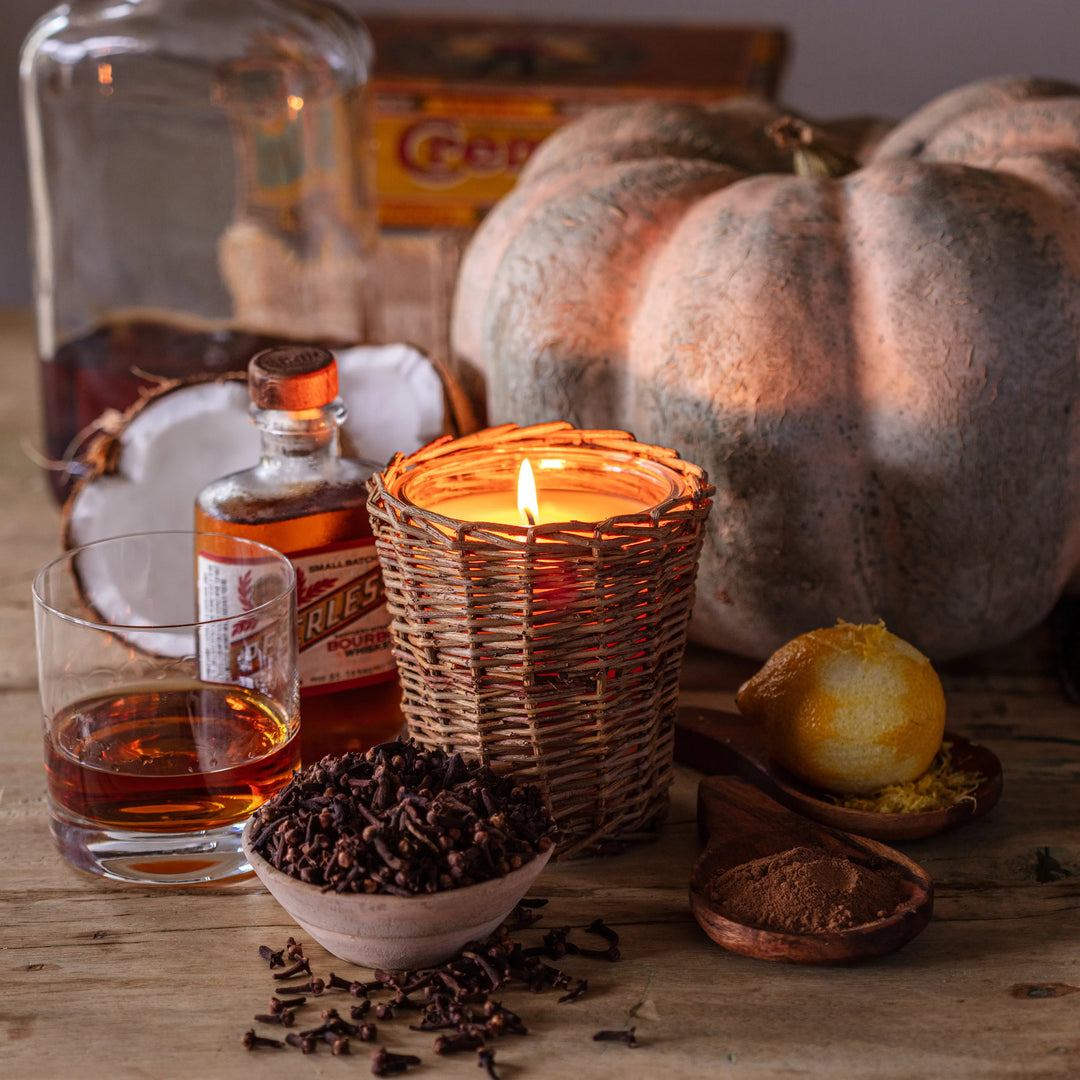 Autumnal still life with pumpkins, a candle, and spices on a wooden surface.